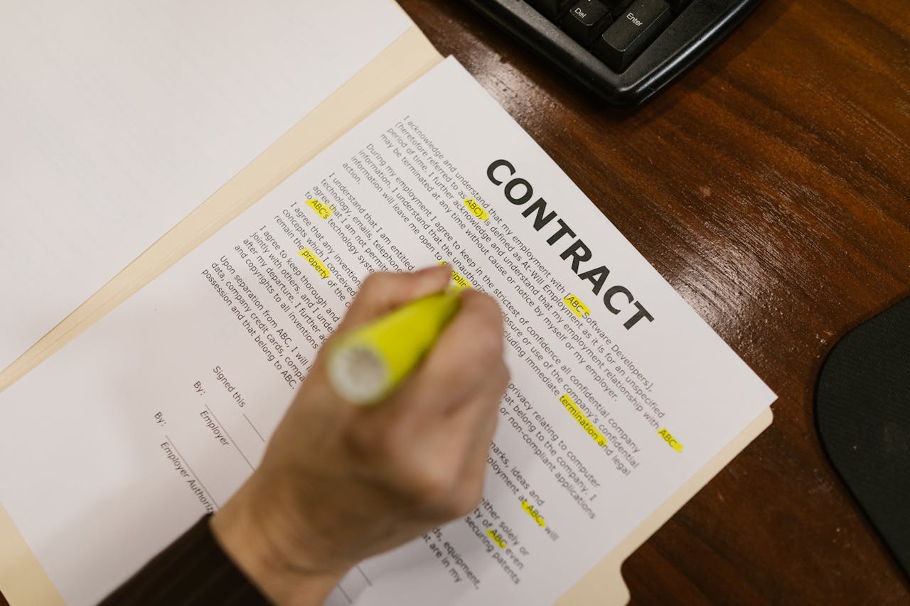 our-story-01 Focused view of a person highlighting text in a contract document on a wooden office desk.